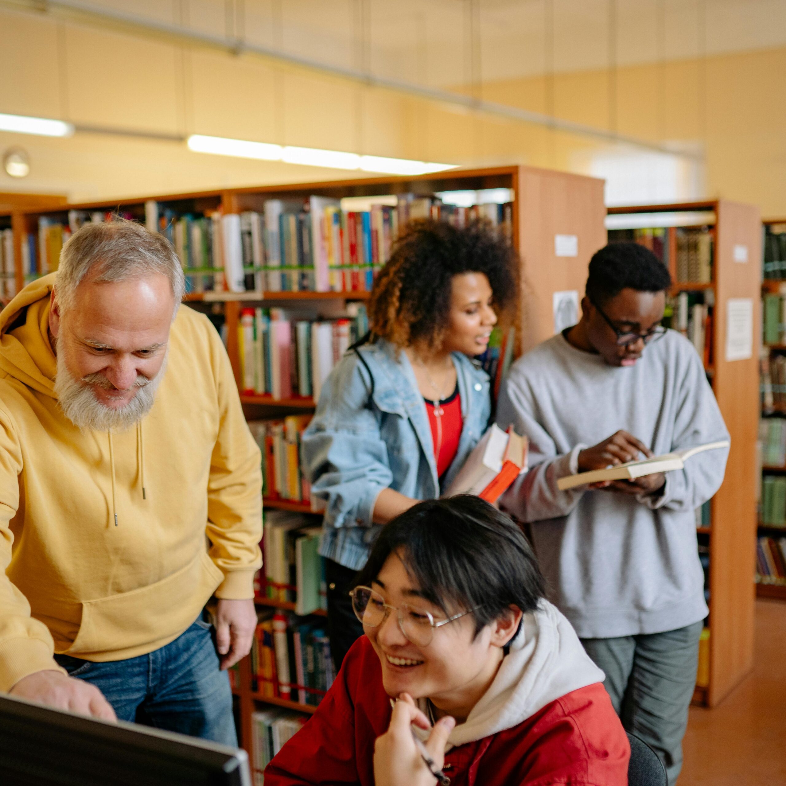 A diverse group of students and a teacher collaborating in a library setting.